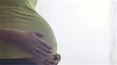  孕妇轻抚摸怀孕肚子站在窗口实拍特写